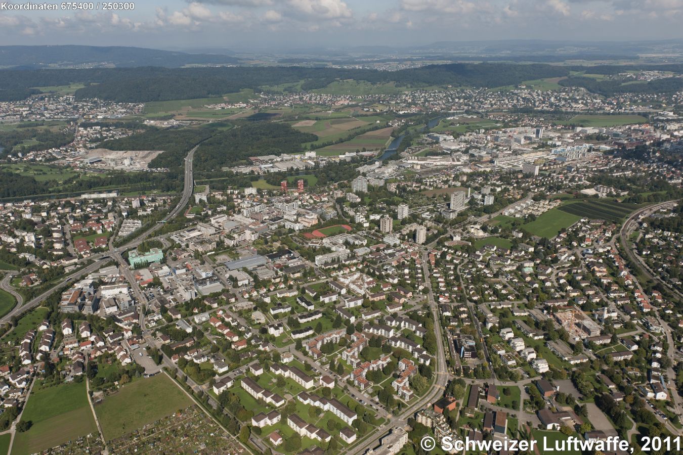 linker Bildrand, doppelstöckige Kreuzung Urdorf-Nord (Position 2'673'907.43, 1'249'750.55): Autobahn A3/A4 und Bernstrasse. - Bildzentrum: Sportplatz Luberten und südlich daran: Kantonsschule Limmattal. Rchtg. Osten (hoher Gebäudekomplex): Spital Limmattal. Rechts Mitte: Schlieren. Im Hintergrund: Unter- und Oberengstringen.